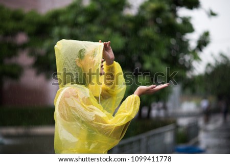 Portrait of the women wearing yellow raincoat while raining in rainy season Royalty-Free Stock Photo #1099411778
