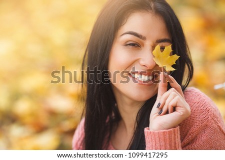 Very beautiful young woman on the autumn background. Close up portrait of smiling young pretty girl in the fall time.