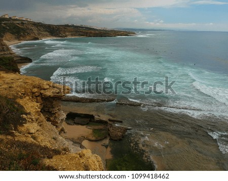 Aerial view from a surf spot with waves and a group of surfers in Ribeira d' Ilhas beach in Ericeira, Portugal