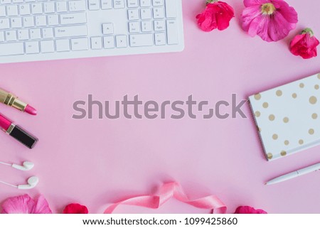 Blogger or freelancer workspace with notebook and pink flowers on pink background