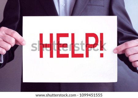 Young businessman holds paper tablet with red inscription "help" in his hands.