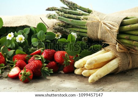 White and green fresh asparagus with a bunch of healthy strawberries