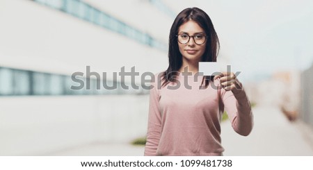 Young pretty woman smiling confident, offering a business card, has a thriving business, copy space to write whatever you want in the university campus