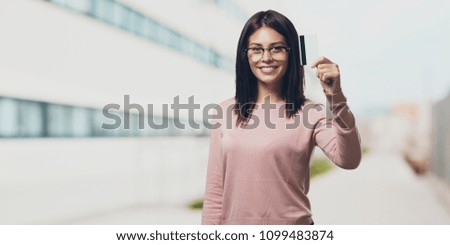 Young pretty woman cheerful and smiling, very excited holding the new bank card, ready to go shopping in the university campus