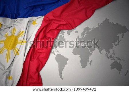 waving colorful national flag of philippines on a gray world map background.