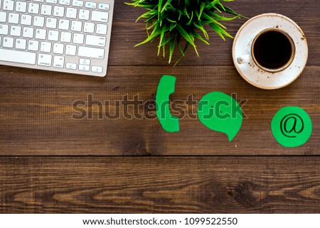 Customer service concept. Concact information. Phone, message, email signs on office work desk with computer on dark wooden background top view copy space