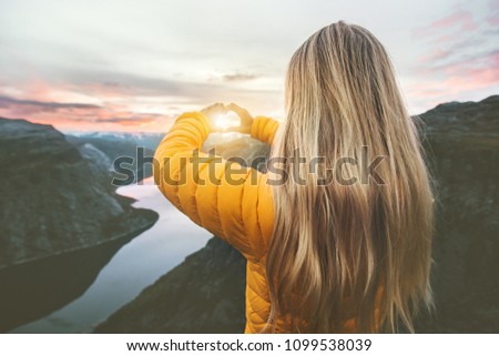 Woman traveling in sunset mountains hands heart symbol shaped Lifestyle emotional concept vacations weekend getaway aerial Norway landscape   Royalty-Free Stock Photo #1099538039