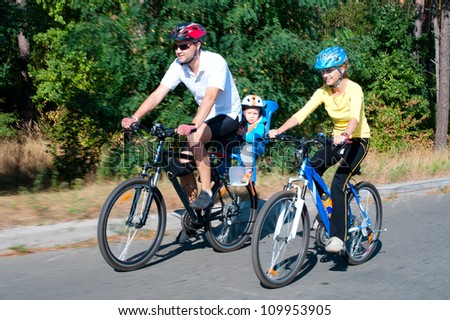 Family on the bikes in the sunny forest.Shot with low shutter speed to achieve motion blur