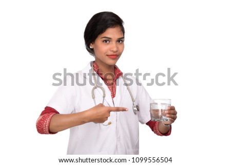 Healthy eating or lifestyle concept:  Smiling female doctor holding a glass of clear fresh water