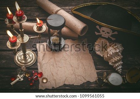 Pirate captain table with crumpled paper page with copy space for treasure map, golden compass, sand watch, scrolls,gemstones and seashell.