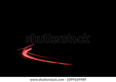 Red car lights in the night forming a curve on a black surrounding.