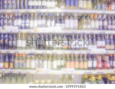 Defocused background with shelves of wine bottles in a supermarket or hypermarket convenience store. Intentionally blurred post production for bokeh effect