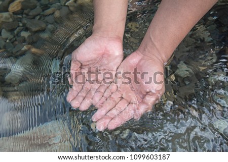 Man hands holding water.Ton Kloi Waterfall ,in the forest at Ban Siam,Ranong,Thailand. Used in editing.Create a graphic,Creative travel business