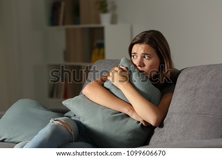 Scared teen at home embracing pillow sitting on a couch in the living room at home Royalty-Free Stock Photo #1099606670