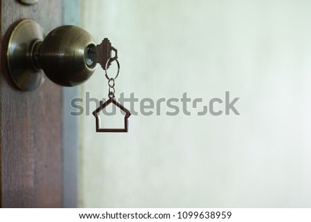 Home key with metal house keychain in keyhole, property concept
