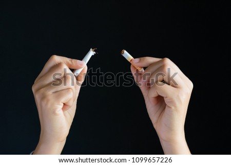 World No Tobacco Day, May 31. STOP Smoking. Close up woman hand breaking, crushing or destroying cigarettes on black background.