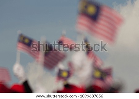 out of focus image of hands waving malaysian flag