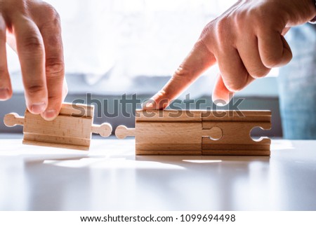 The man points to the same two incompatible jigsaw puzzles. The concept of misunderstanding, non-conforming elements, mutually exclusive statements. Royalty-Free Stock Photo #1099694498