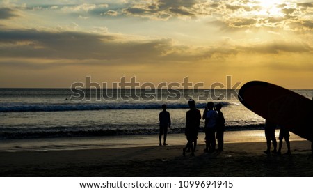 Silhouette of tourist taking picture and walking at sunset on Kuta beach in Bali