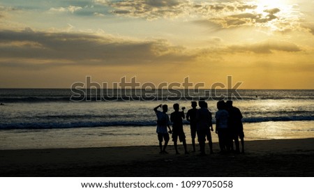 Silhouette of tourist taking picture and walking at sunset on Kuta beach in Bali