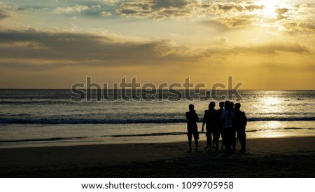 Silhouette of tourist taking picture and walking at Kuta Beach in Bali during sunset