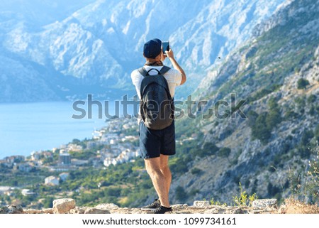 A man takes a picture on a smartphone from the mountains