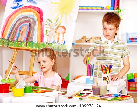 Two kid painting at easel in school.