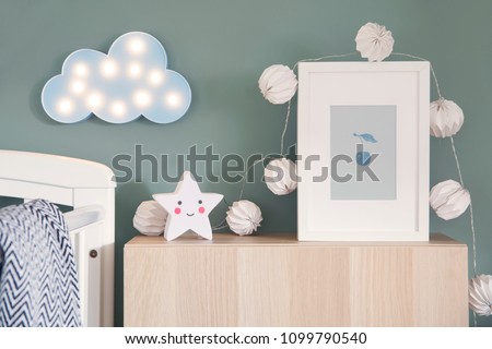 Stylish nursery interior with mock up photo frame , cotton lamps, star and blue cloud. Green background wall.
