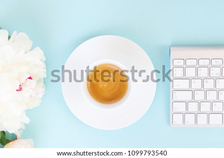 Flat lay home office workspace with cup of coffee, white modern keyboard and flowers