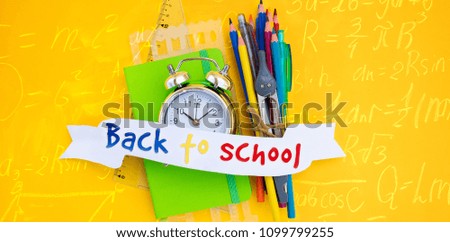 back to school concept - alarm clock and school supplies with back to school text on ribbon, top view scene with math formulas banner