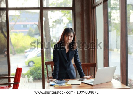 Happy young woman taking notes while talking on mobile phone.