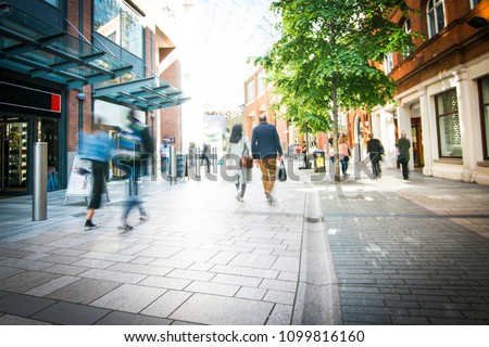 Anonymous shoppers walking on a shopping high street Royalty-Free Stock Photo #1099816160