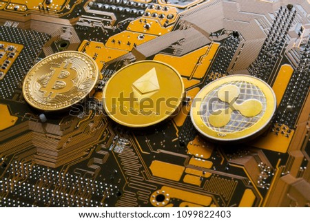 Bitcoin, Ethereum and Ripple coins - largest cryptocurrencies by market capitalization lying on computer motherboard, cryptocurrency investing concept Royalty-Free Stock Photo #1099822403