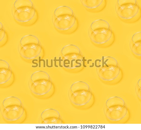 Unusual creative modern trendy photo with simple glass vase on the yellow background.