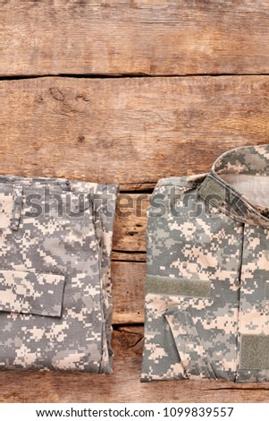 Set of soldiers uniform on wood. Flat lay, top view. Wooden desk surface background.