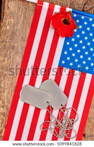 Dog tags, red poppy and american usa flag. Wooden desk bakground.