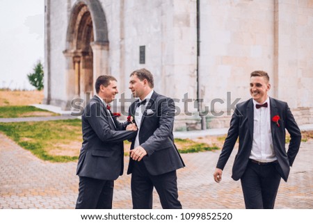 Young groom and his funny friends groomsman posing for camera. Group of young men with bow tie. Cheerful friends. friends outdoors. Wedding day.