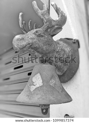 Head of Deer statue made of metal hanging bell on the wall in front of a restaurant in Thailand. This image was blurred or selective focus. Black and white picture.