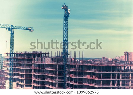 tower cranes against the blue sky. House under construction. Industrial skyline