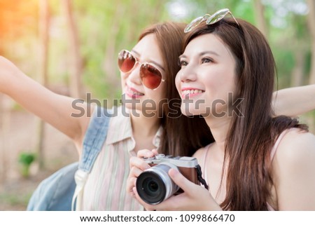two beauty woman take camera look somewhere and go travel happily in the forest