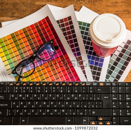 Color palette, guide of paint samples catalog. designer's objects lie on wooden table - glasses, coffee plastic cup, keyboard. top view. 