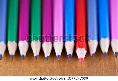 black lead pencils lie in a row, one pencil has a red core and put forward , small depth of sharpness