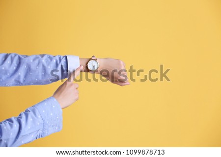 Young woman with wristwatch on color background. Time concept Royalty-Free Stock Photo #1099878713