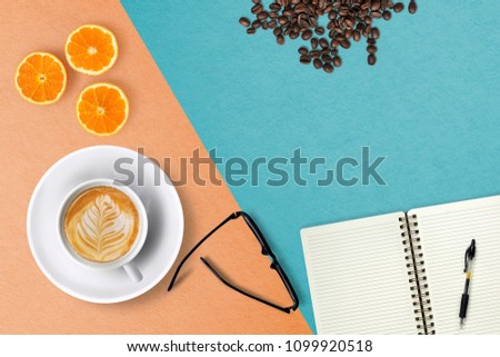 Fat lay photo of workspace desk with coffee cup, eyeglasses and pen, open notebook on paper colorful background texture, of free space for your copy, view from top.