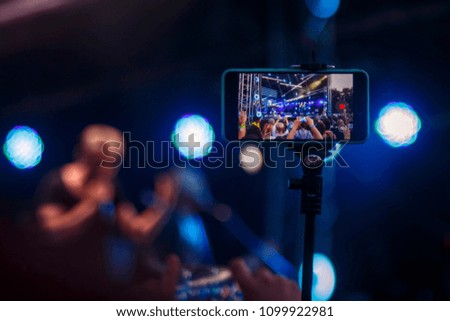 Young people shoot photos or video of a concert on smartphones.