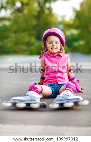 Attractive smiling child in roller skates and protective equipment