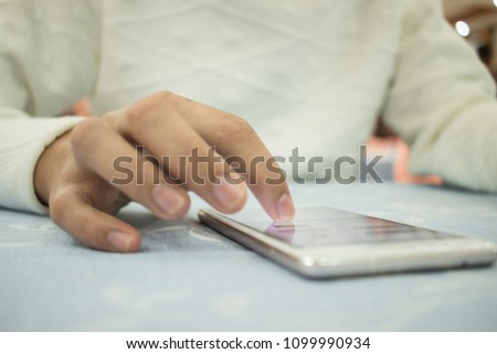 Online searching social networks by Smartphone Concept: Hand of young man pointing finger on blank screen smart phone, using hand clean gadget or typing sms message to his friends on table background