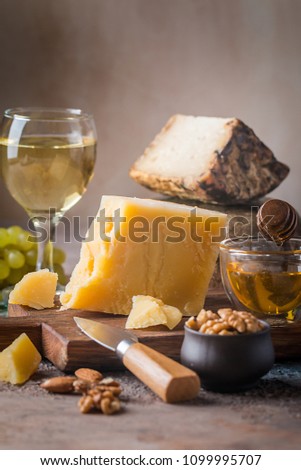 various types of cheese with honey, grapes and wine on rustic background
