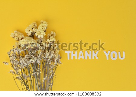 Flat lay image from above: the words "THANK YOU" with Bouquet of dried flowers on yellow background. Thank you concept.