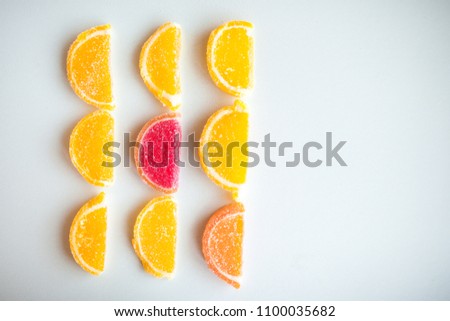 conceptual photo of marmalade pieces in shape of lemon slices and one watermelon/grapefruit and orange shaped piece on white background. Sweet food background.
